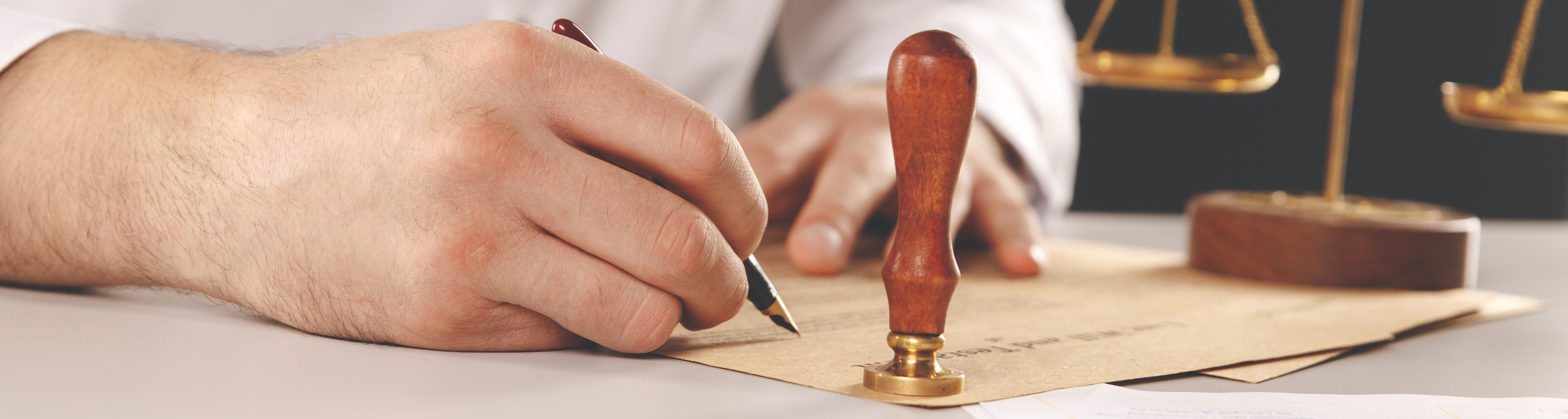 Hand signing documents with a notary stamp next to it.